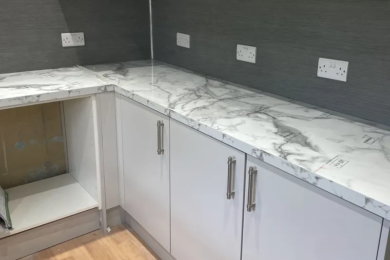 Fitted kitchen with grey units, marble-effect worktops and new sockets above the worktop